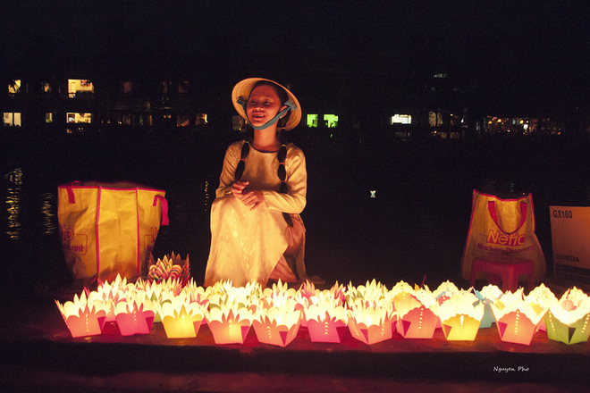 A pretty girl wears a conical hat with smiley face selling paper lanterns