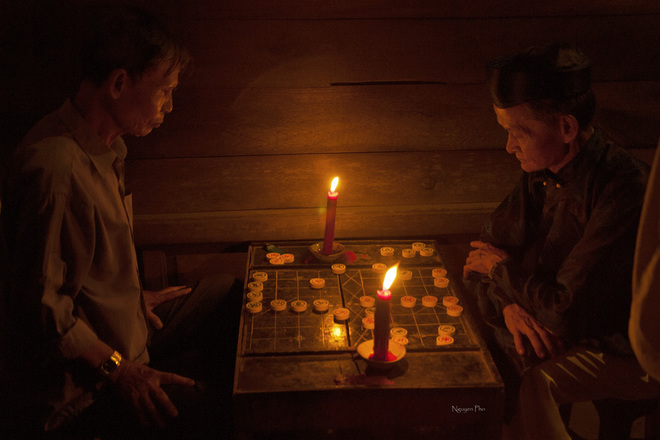 Below dim light of candle, two older men with tense face find out how to win the other.